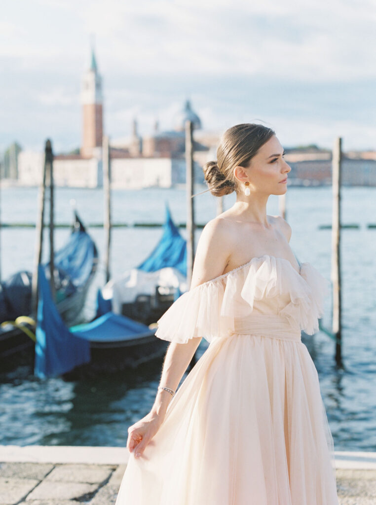 A woman standing in front of Gondolas in Venice